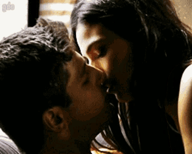 a man and a woman are kissing on a bed in a dark room .