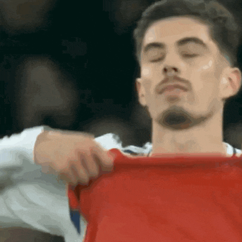 a man with his eyes closed is taking off a red shirt