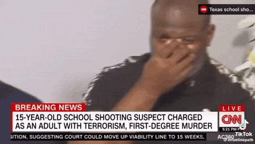 a man is covering his face while watching a news report