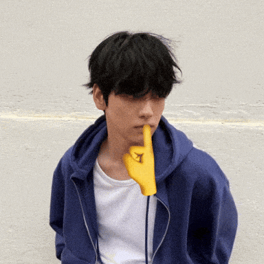 a man wearing a blue hoodie has a yellow finger on his mouth