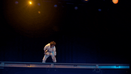 a person in a white karate uniform is standing on a stage