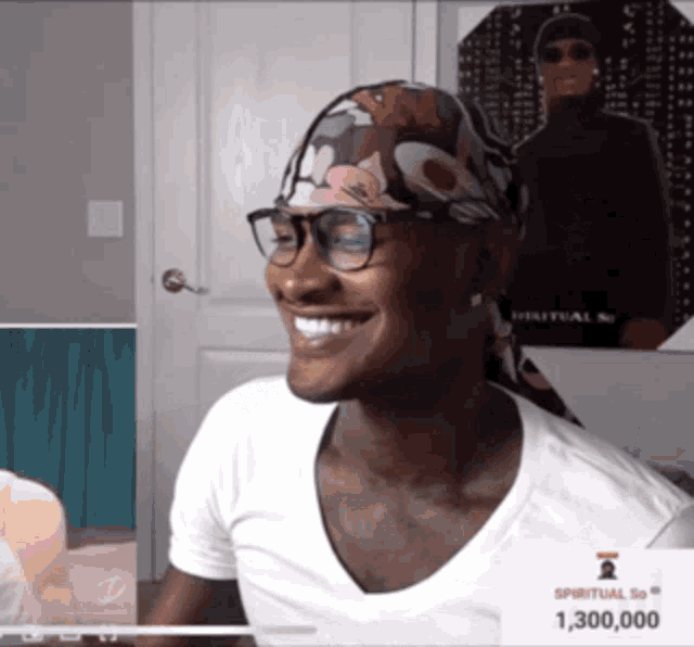 a man wearing glasses and a head scarf is smiling in front of a poster that says spiritual so