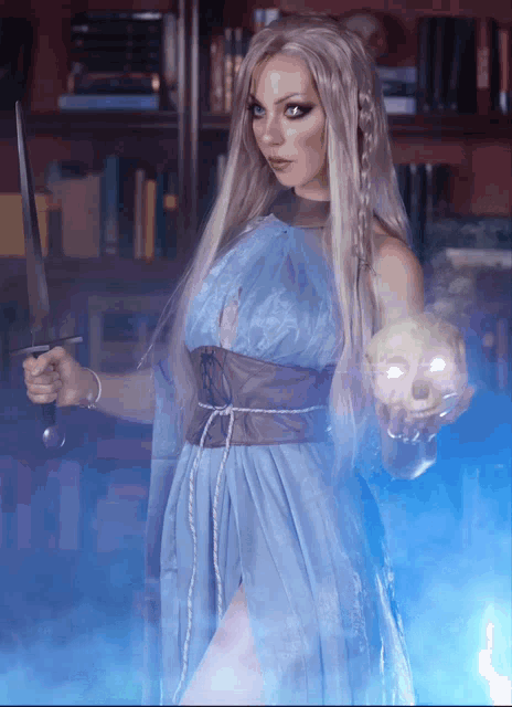 a woman in a blue dress holds a sword and a skull in her hands