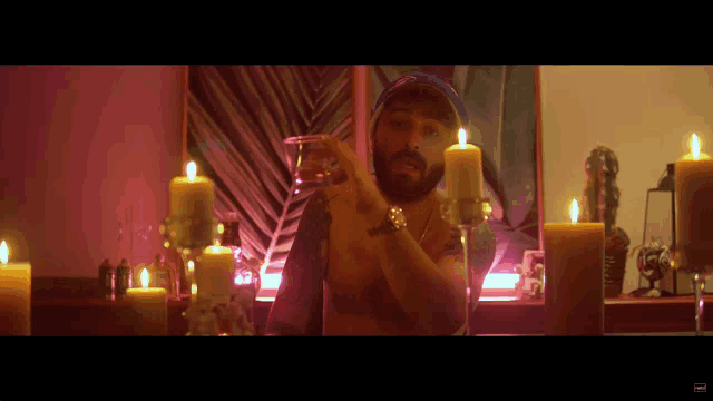 a man with a beard is standing in front of candles