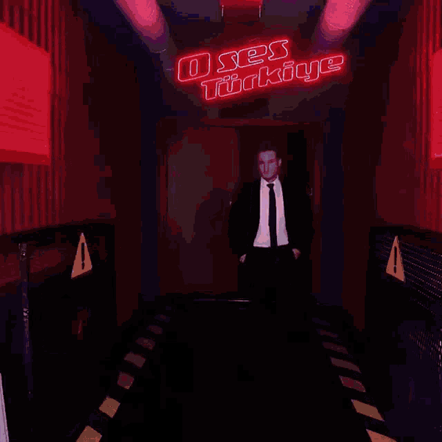 a man in a suit and tie is standing in front of a sign that says o ses turkeye