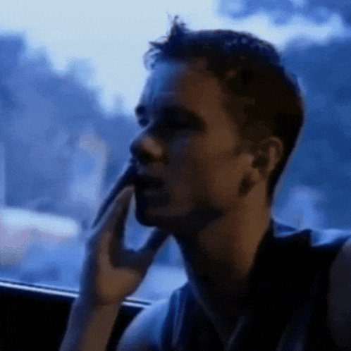 a man is talking on a cell phone while looking out of a window .