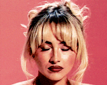 a close up of a woman 's face with her eyes closed against a pink background