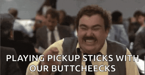 a man with a mustache is laughing while playing pickup sticks with his buttcheeks .
