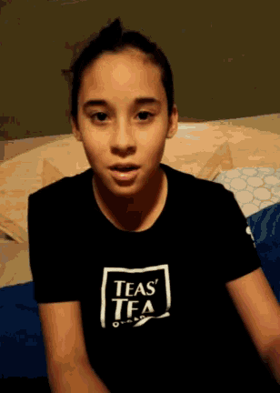 a young girl wearing a black teas tea t-shirt