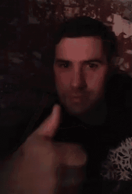 a man in a black shirt is giving a thumbs up sign