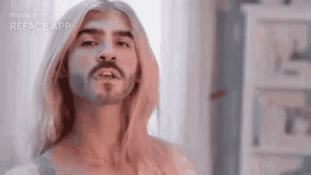 a man with long blonde hair and a beard is making a face .