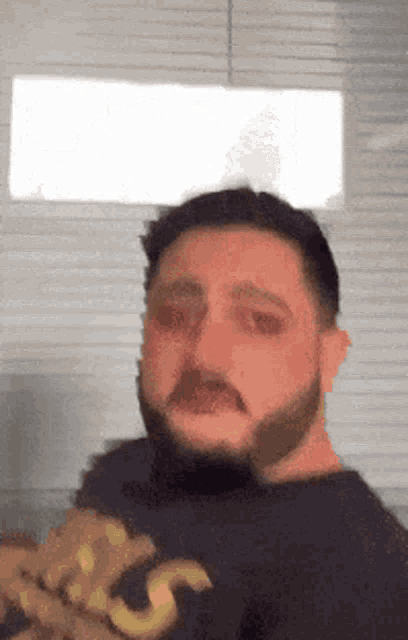a man with a beard is wearing a black shirt with a yellow s on it