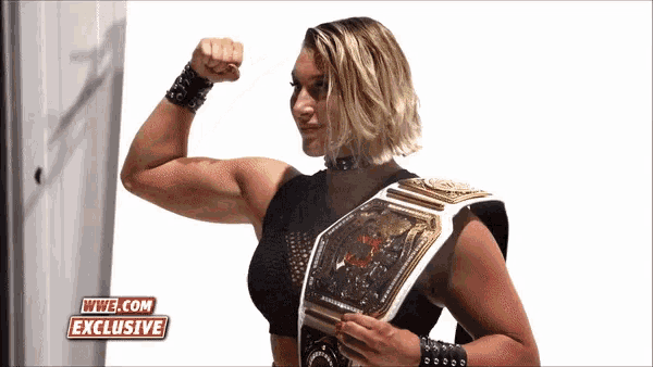 a woman flexes her muscles in front of a wwe.com exclusive logo