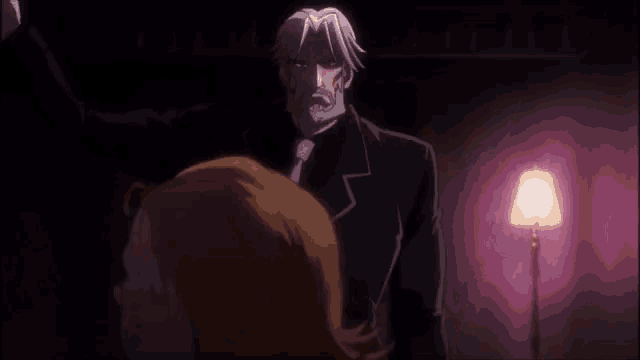 a man in a suit and tie is standing next to a woman in a dark room .