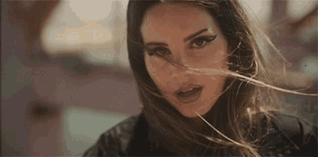 a close up of a woman with long hair blowing in the wind