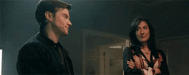 a man and a woman are standing next to each other in a room .