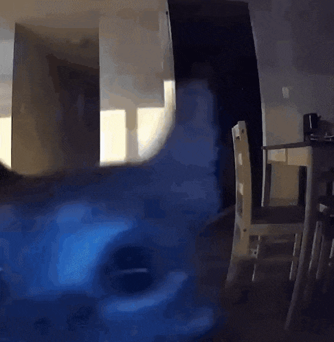 a dark room with a table and chairs and a blue light coming out of the door