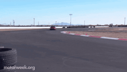 a red car is driving on a track with motorweek.org written on the bottom of the screen