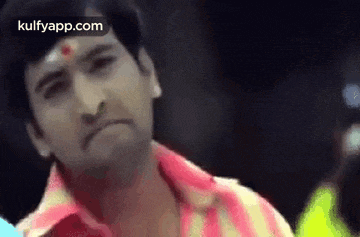 a close up of a man 's face with a red bindi on his forehead .