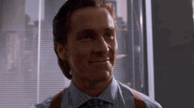 a man wearing a blue shirt and red suspenders smiles for the camera