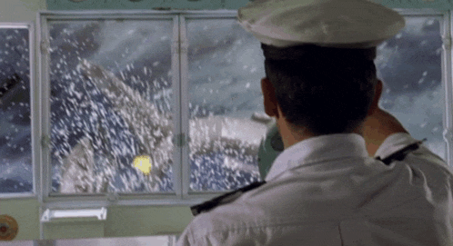 a man in a white uniform looks out a window at a snowy scene