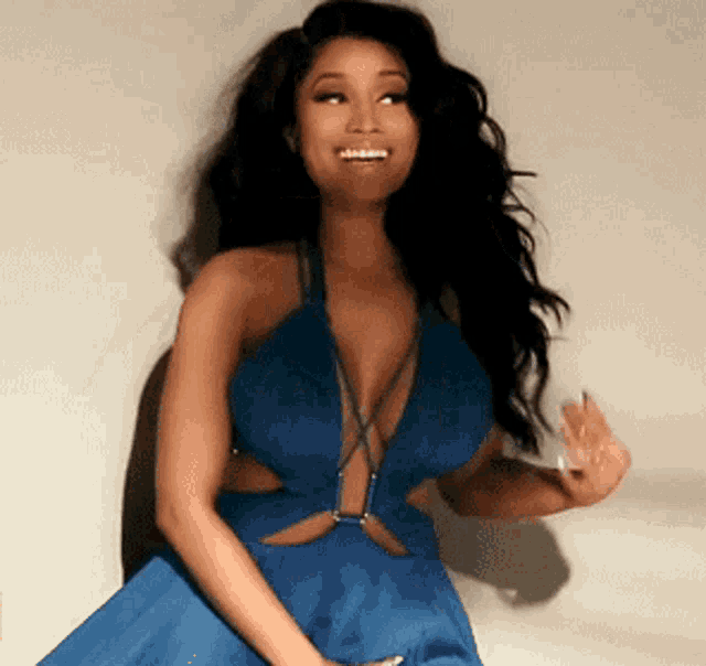 a woman in a blue dress with a plunging neckline is smiling