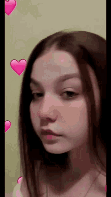a close up of a girl 's face with pink hearts on the background