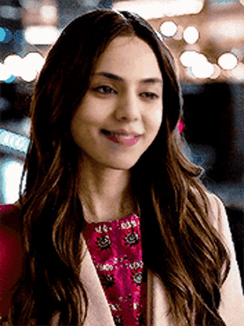 a woman wearing a pink coat and a red dress smiles