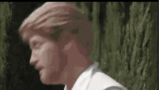 a close up of a man 's face in front of a tree .