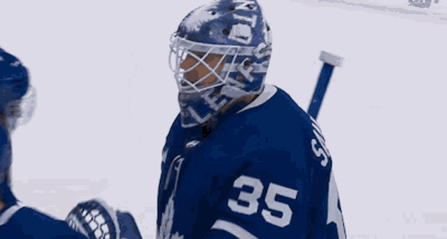 a hockey player with the number 35 on his jersey talks to another player