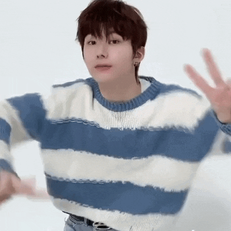 a young man wearing a blue and white striped sweater is waving his hands .