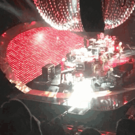 a group of people are playing instruments on a stage in front of a large red heart shaped stage .