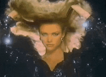 a woman with a huge wig on her head is surrounded by stars
