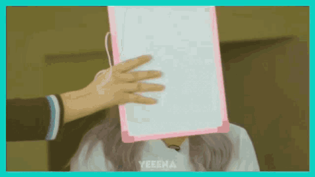 a woman is holding a white board in front of her face .