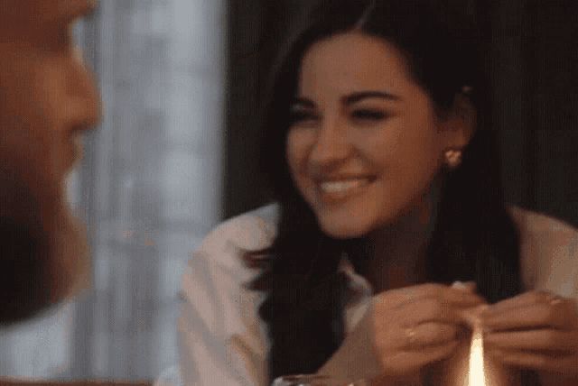 a woman is smiling while holding a candle in front of a man