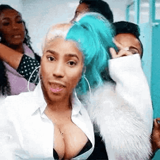 a woman with blue hair and a plunging neckline is taking a selfie with a group of people .
