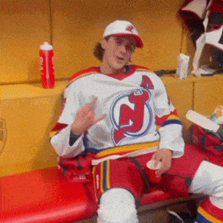 a man in a jersey with the letter j on it is sitting on a bench