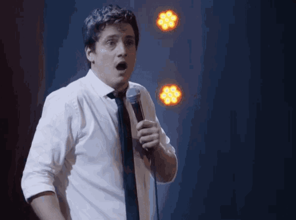 a man in a white shirt and tie holds a microphone