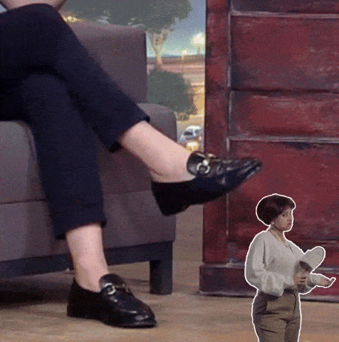 a woman wearing black shoes sits on a couch next to a smaller woman