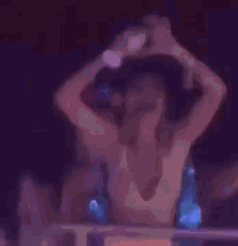 a woman in a bikini is dancing in a dark room .
