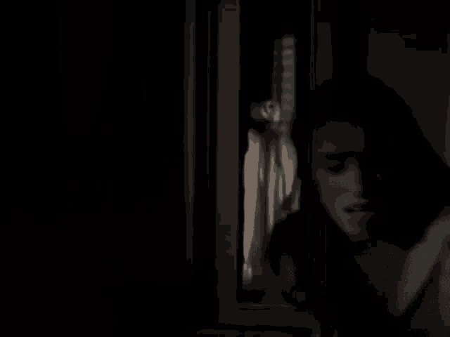 a man is standing in a dark room with a ghost behind him .
