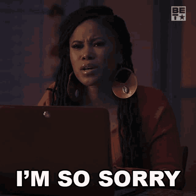 a woman sitting in front of a laptop with the words i 'm so sorry on her face
