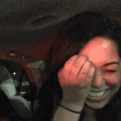 a woman covering her face in a car with her hand