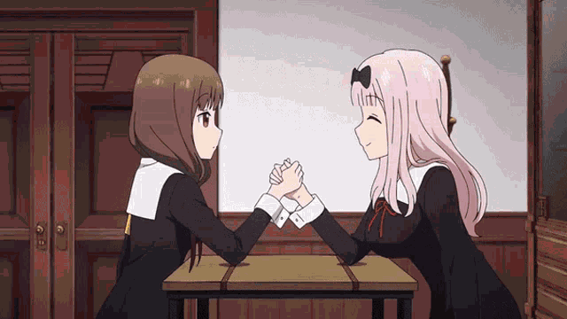 two anime girls are sitting at a table with their hands clasped