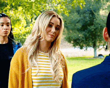 a woman wearing a yellow cardigan and a yellow and white striped shirt smiles
