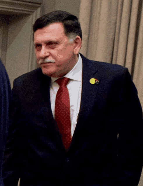 a man in a suit has a yellow pin on his jacket