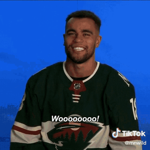 a man wearing a green minnesota wild jersey says woooooo
