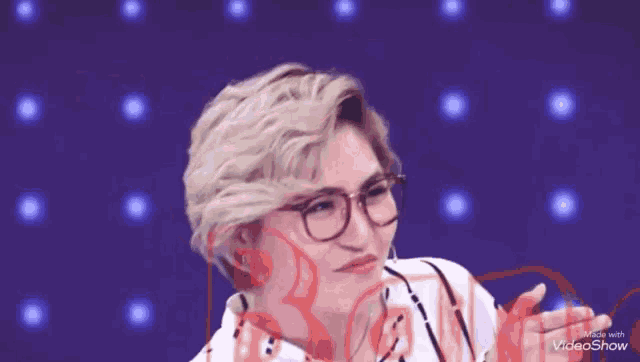 a woman wearing glasses is making a funny face with her hands