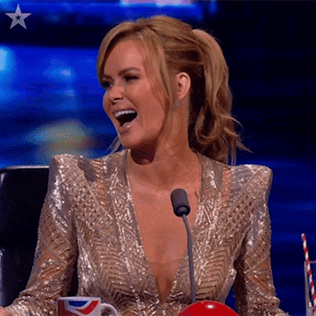 a woman in a gold dress is sitting in front of a microphone and smiling