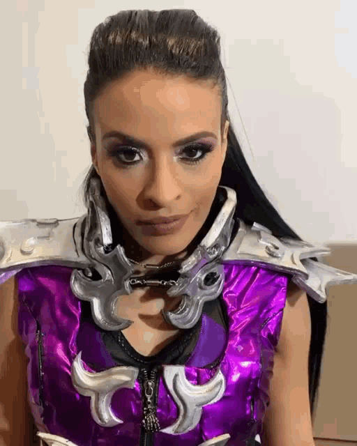 a woman wearing a purple and silver costume looks at the camera